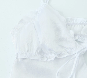 Detailed view of white midi dress with delicate ruffles and thin shoulder straps