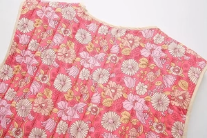 Détail rapproché d'un gilet matelassé en coton rose avec imprimé floral et passepoil