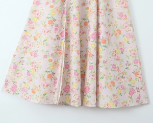 Détail de la robe en coton rose à fleurs avec une fente haute sur le côté