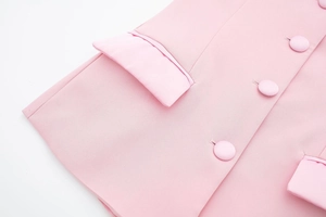 Détail d'un tailleur en satin rose avec boutons recouverts et poches à rabat