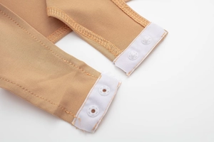 Detail view of the snap fastener closure on nude stretch knit bodysuit with white buttons