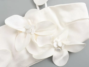 Detail of elegant white satin top featuring a large 3D fabric flower decoration