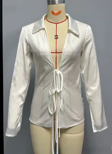 Detailed view of white satin shirt featuring front bow ties and smooth silk-like fabric