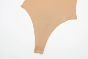 Macro detail of nude bodysuit showing durable double-stitched seams and elastic fabric