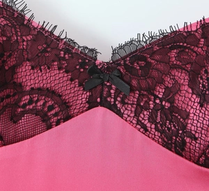 Détail de la robe en satin rose avec dentelle cils noire et petit nœud au décolleté