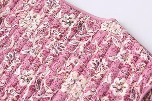 Close-up of pink floral quilted jacket featuring vertical stitching and piping detail