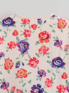 Detailansicht des Blumenmusters mit roten und rosa Blüten auf der beigen Baumwolljacke