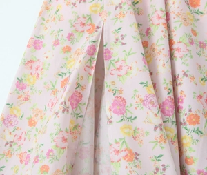 Détail du tissu en coton rose à motifs floraux colorés avec une fente haute élégante