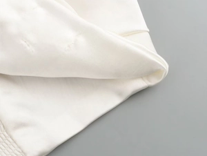 Detailed macro view of white satin fabric texture and elastic ruched hem design