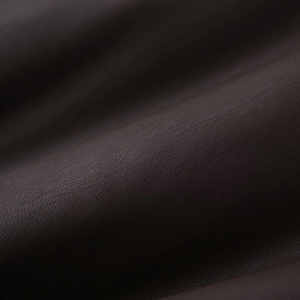 Macro shot of high-quality dark brown leather featuring a delicate lychee grain texture