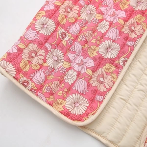 Détail du gilet matelassé à fleurs montrant le tissu réversible et les coutures