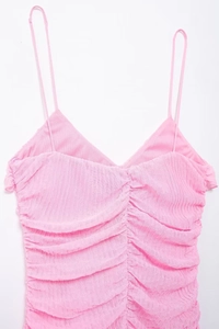 Dettaglio dell'abito rosa con arricciature, spalline sottili e scollo a V testurizzato