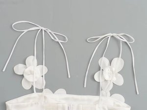 Close-up of white summer top with 3D floral accents and delicate tie-up straps