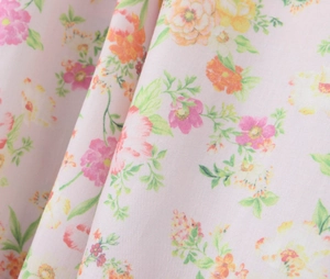 Détail du tissu en coton rose clair avec imprimé floral et drapé élégant et doux