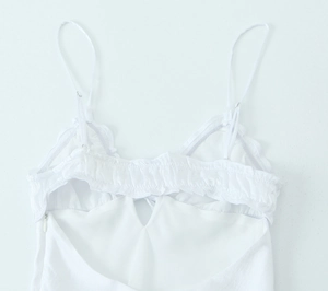 Close-up of white satin midi dress featuring tiered ruffle neckline and adjustable straps