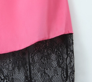 Gros plan de tissu satiné rose avec bordure en dentelle noire et broderies florales