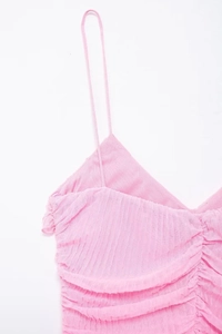 Dettaglio di pieghe rosa a strati e texture arricciata su un abito estivo a spalline