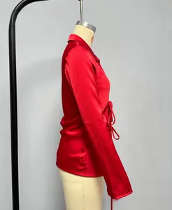 Detailed side view of a red satin shirt featuring a stylish side bow tie and long sleeves