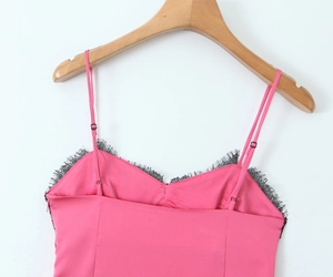Détail d'un caraco en satin rose vif avec dentelle noire et bretelles réglables