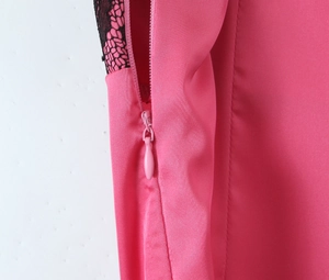 Détail de la fermeture éclair invisible latérale et de la dentelle noire sur la robe rose