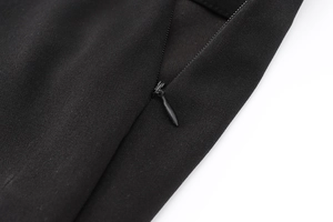 Dettaglio di una tuta in crespo nero con chiusura a cerniera invisibile impeccabile