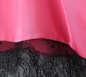 Détail du tissu satiné rose avec bordure en dentelle florale noire et texture lisse