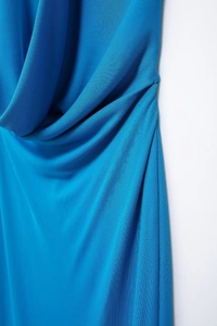 Detailed close-up of bright blue pleated fabric with soft drapes and fine texture