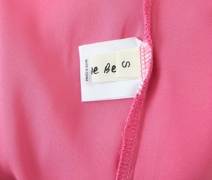 Détail des étiquettes intérieures de la robe rose montrant la taille S et l'origine