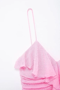 Dettaglio di un abito estivo rosa con tessuto a pieghe e volant decorativi sullo scollo