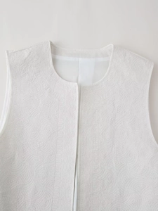 Gros plan du gilet blanc matelassé montrant la broderie circulaire et la texture du tissu