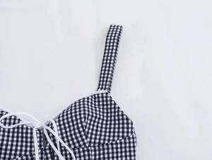 Close-up of black and white gingham corset top with white lace trim and lace-up detail
