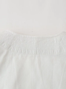 Détail de la veste blanche en coton montrant une broderie florale et un col plissé