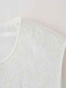 Détail de gilet blanc avec broderie de vagues complexe et encolure ronde élégante