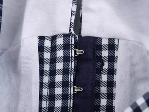 Detailed close-up of hook-and-eye closure on a blue plaid corset top with white fabric