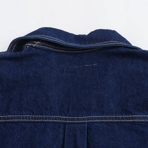Nahaufnahme eines dunkelblauen Jeanshemdes mit kontrastierenden orangefarbenen Nähten