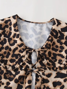 Detail of leopard print blouse featuring ruffled Peter Pan collar and bow tie closure