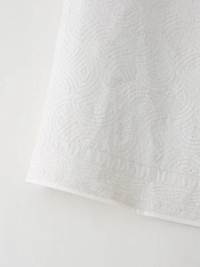 Gros plan sur un tissu matelassé blanc avec broderies circulaires et texture ondulée