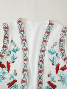 Close-up of white vest featuring colorful ethnic embroidery and textured fabric detail