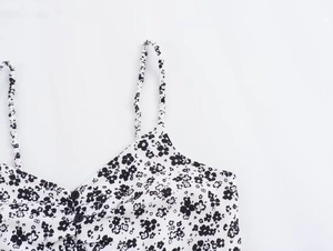 Detailed view of white floral camisole top with black flower print and thin shoulder straps
