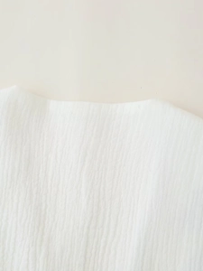 Close-up of a white sleeveless top neckline showing vertical crinkle cotton texture