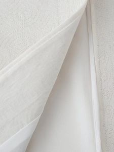 Détail de gilet blanc avec broderie matelassée concentrique et doublure en satin lisse
