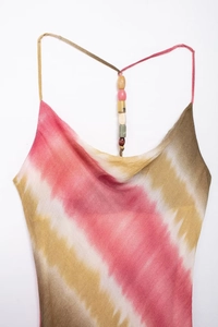 Dettaglio di abito midi con scollo a cappuccio, motivi tie-dye e spalline con perline