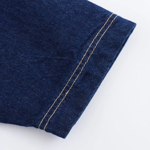 Detail aus dunkelblauem Denim mit verstärkten gelben Doppel-Kontrastnähten am Saum