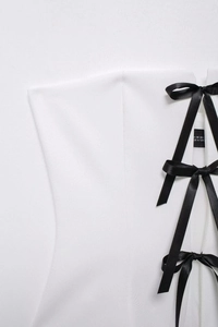 Detail of white slim-fit top featuring black satin ribbon lace-up design and XS size label