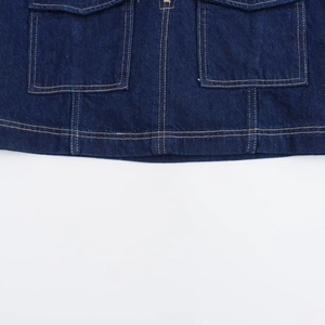 Detailansicht aus dunkelblauem Denim-Stoff mit orangefarbenen Kontrastnähten und Doppeltaschen