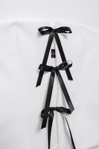 Detail of white off-shoulder top with three black ribbon bows and Turkey size label
