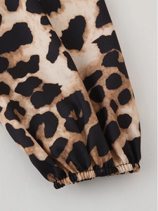 Detail shot of leopard print shirt showing elastic ruffled cuffs and woven fabric texture