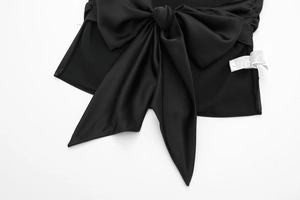 Detail of elegant black satin bow tie decoration and white care label on the fabric