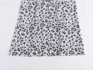 Close-up of black and white floral print dress with decorative front button details
