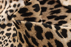 Detailed close-up of leopard print fabric texture with smooth silky sheen and drape